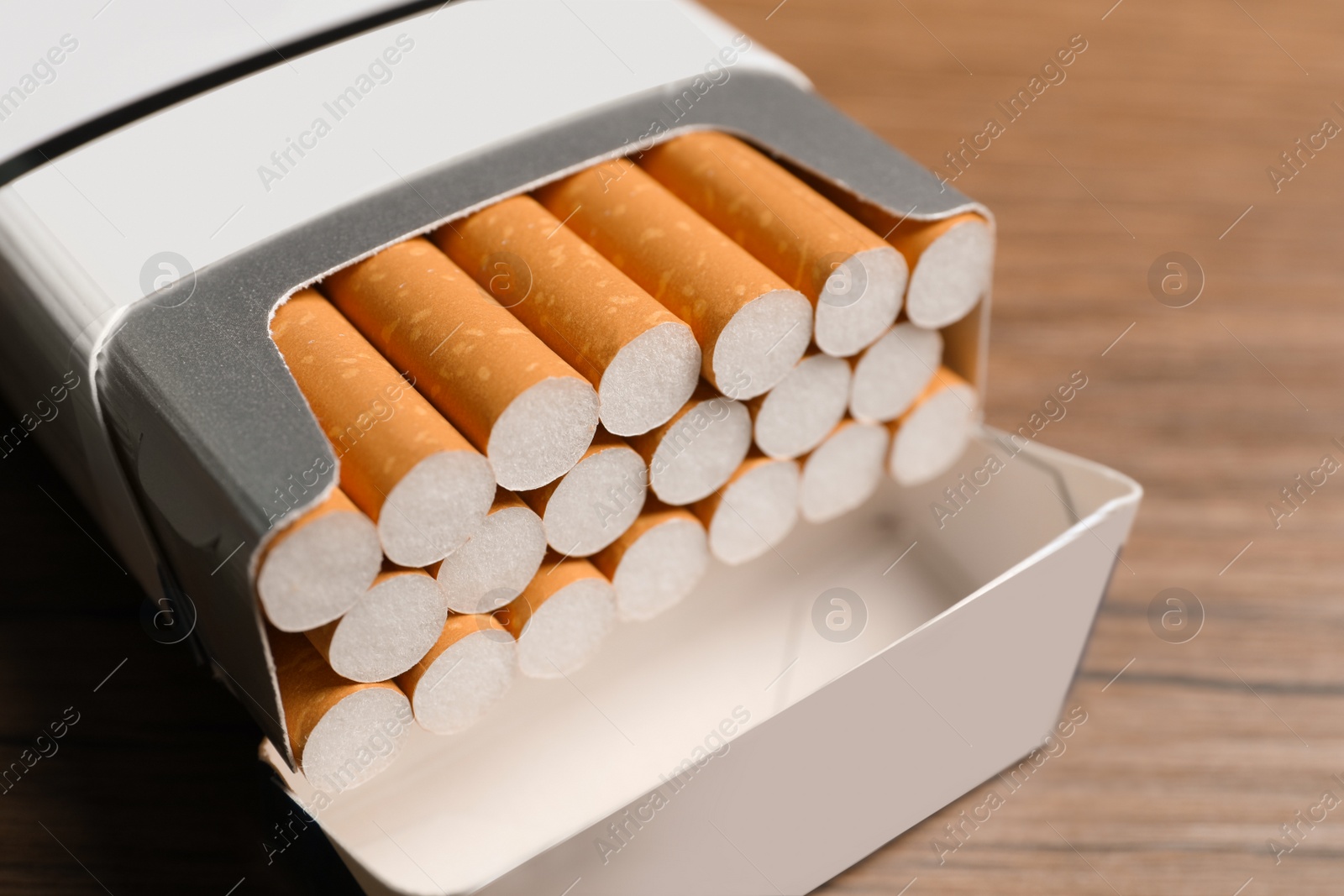 Photo of Cigarettes with orange filters in pack on table, closeup