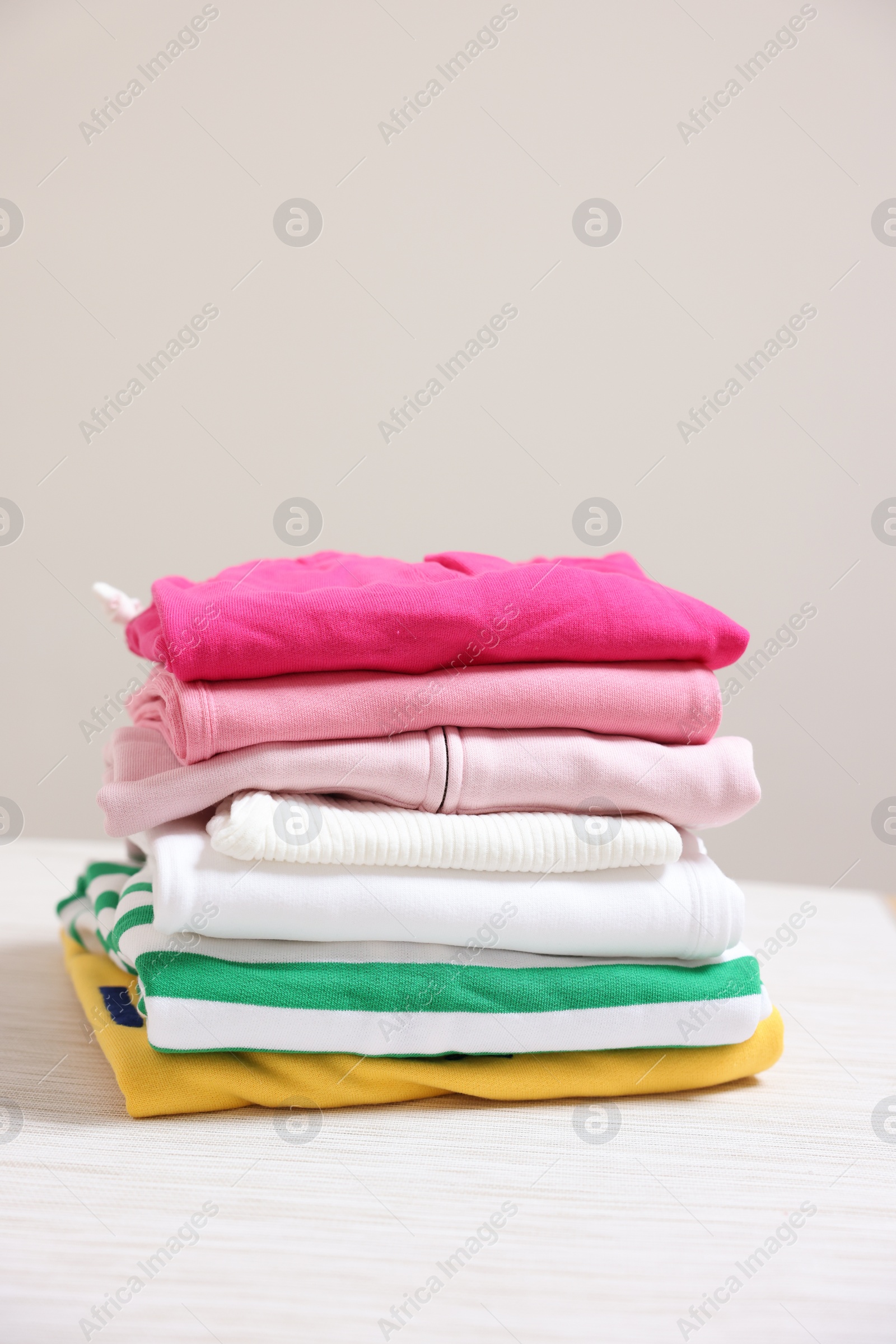 Photo of Stack of folded clothes on table against beige background