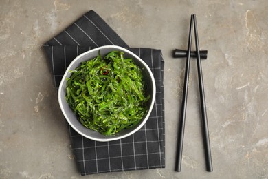 Photo of Japanese seaweed salad served on grey table, flat lay