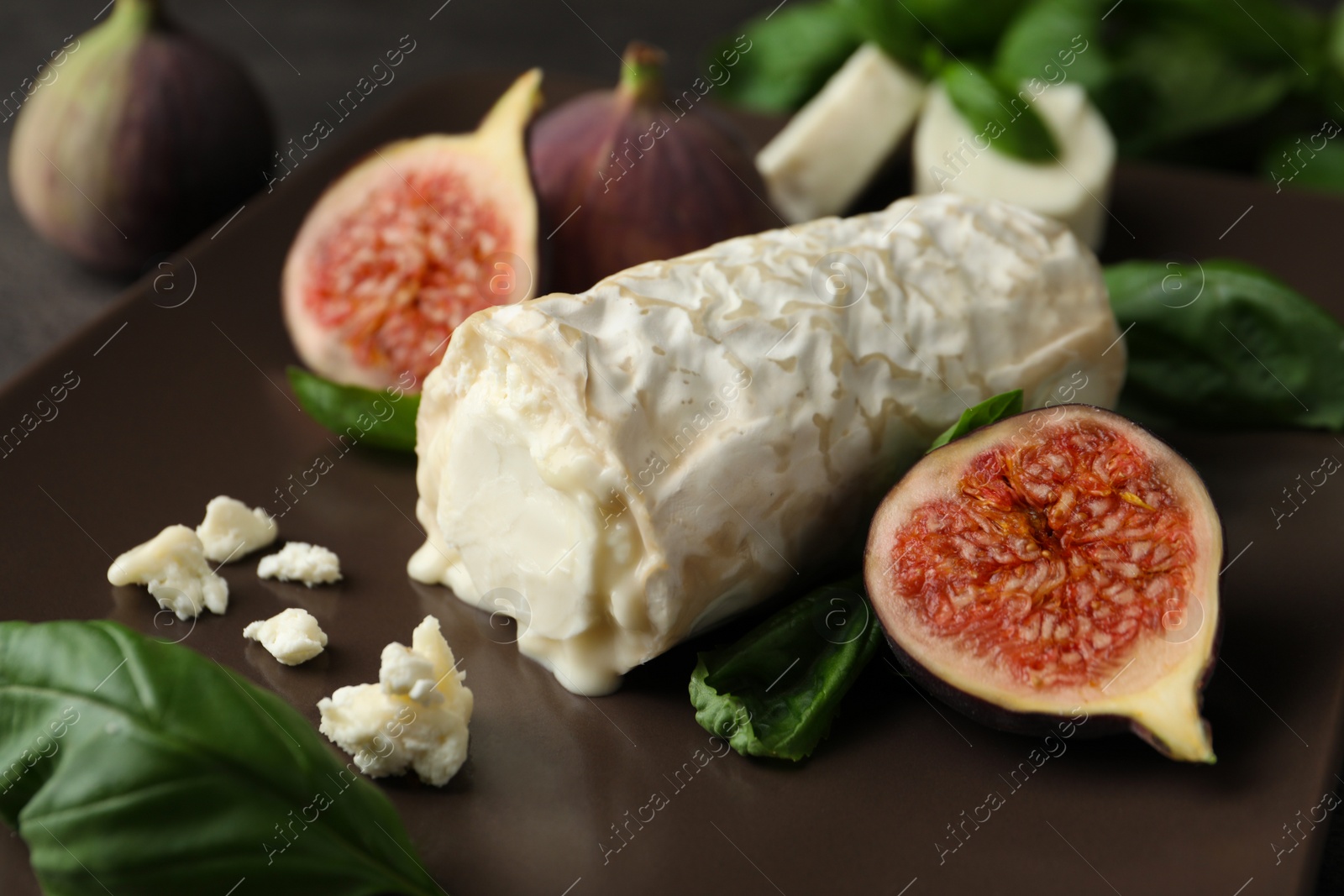 Photo of Delicious goat cheese with figs and basil on plate, closeup