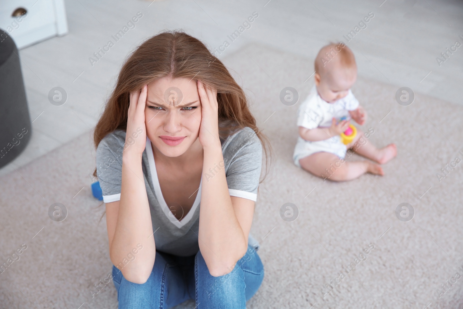 Photo of Young mother suffering from postnatal depression and little baby in room