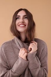 Photo of Portrait of beautiful young woman in warm sweater on brown background