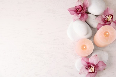 Photo of Flat lay composition with zen stones, candles and flowers on wooden background. Space for text