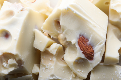 Photo of Pieces of white chocolate with nuts as background, closeup