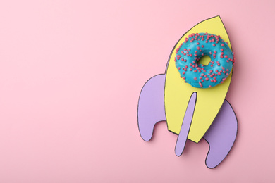 Photo of Rocket made with donut and paper on pink background, top view. Space for text
