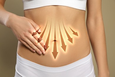 Image of Healthy digestion. Woman with down arrows on her belly against dark beige background, closeup