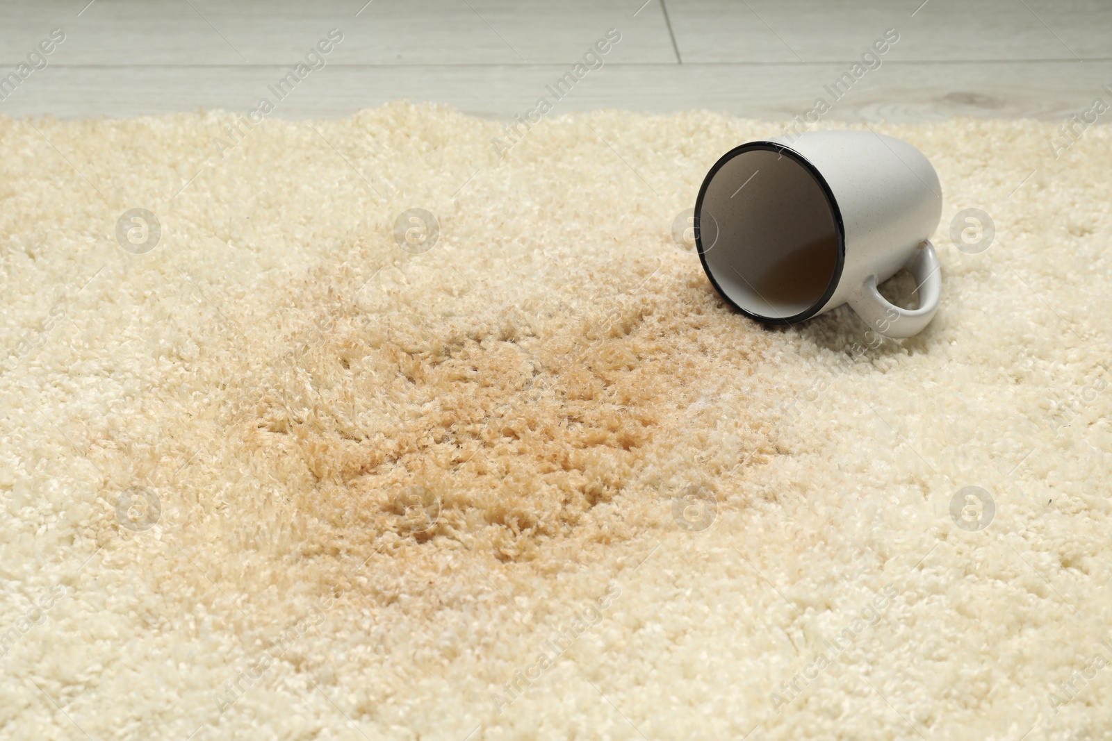 Photo of Overturned cup and spilled drink on beige carpet, closeup
