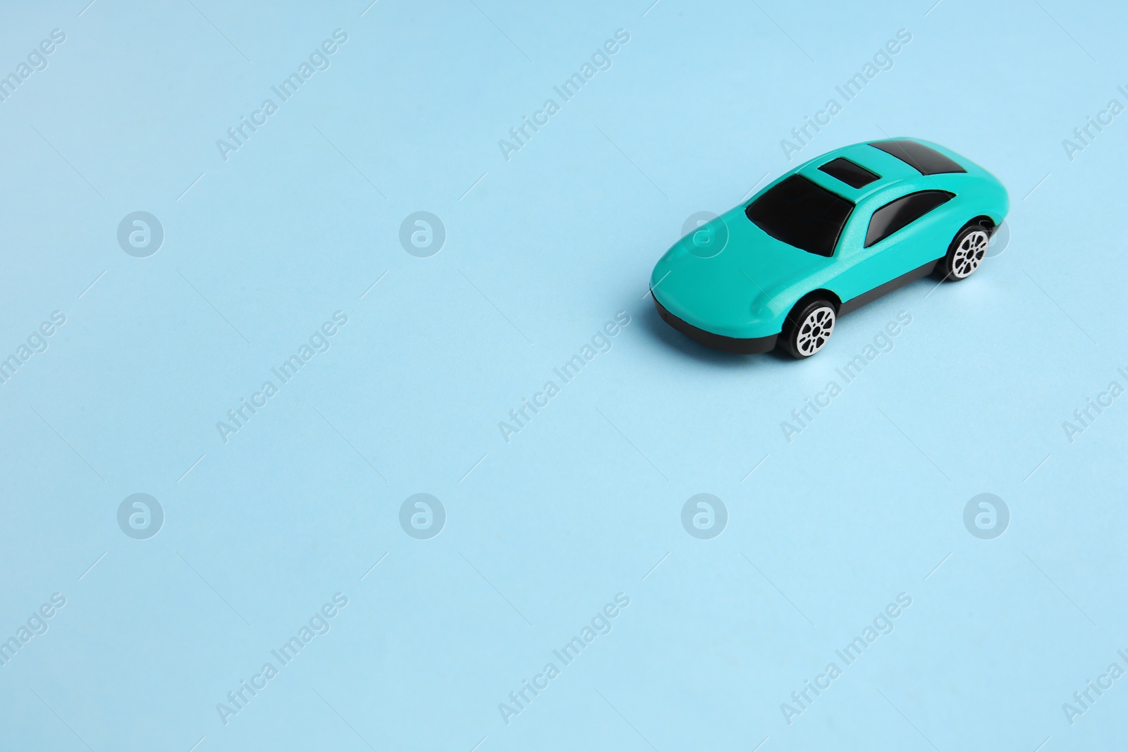 Photo of One bright car on light blue background, space for text. Children`s toy