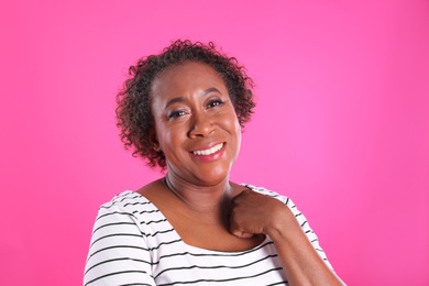 Portrait of happy African-American woman on pink background