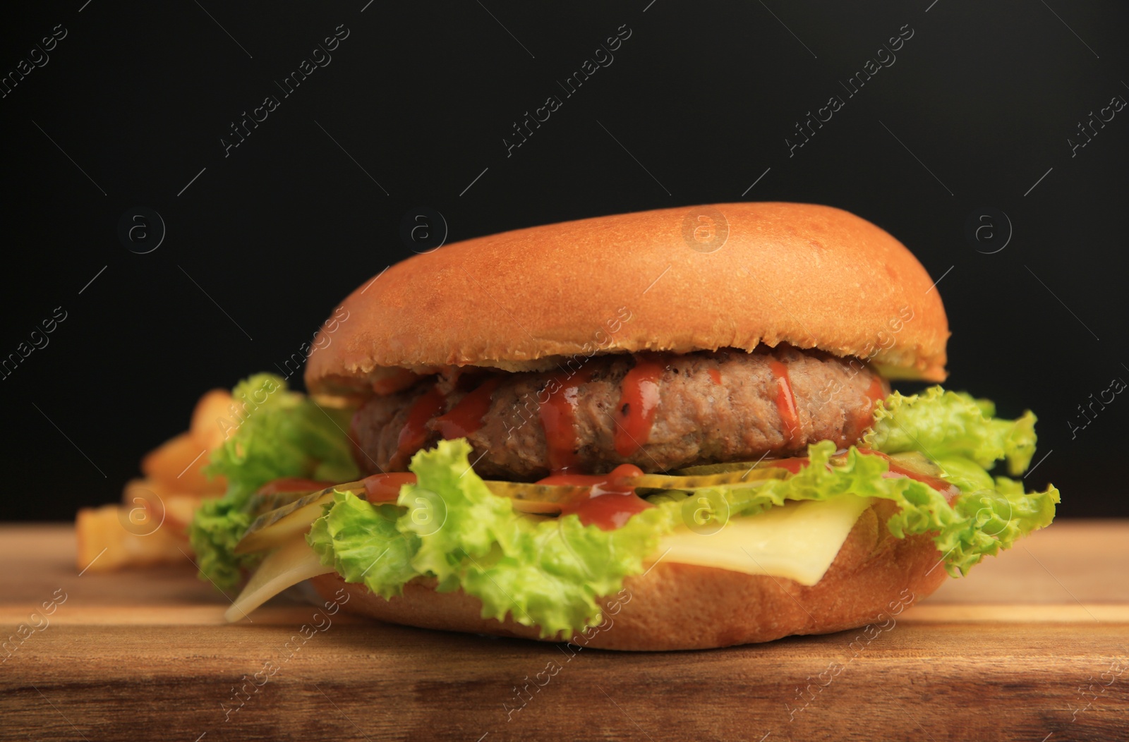 Photo of Tasty burger with patty, lettuce and cheese on wooden table, closeup