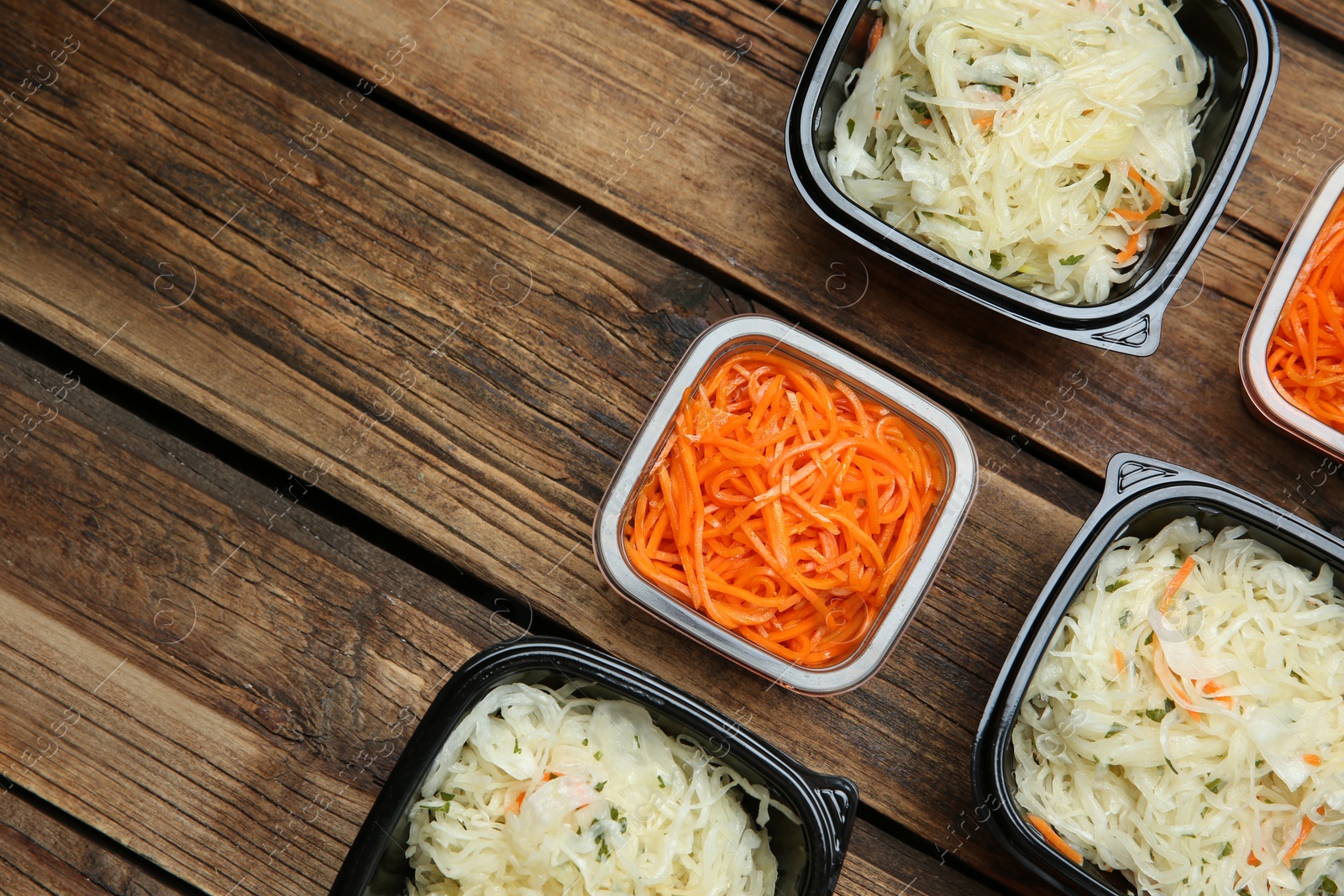 Photo of Plastic containers with tasty vegetable salads on wooden table, flat lay and space for text. Food delivery service