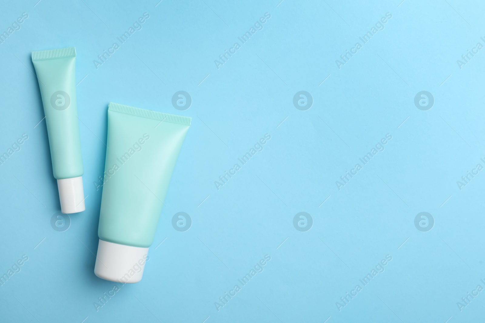 Photo of Set of luxury cosmetic products on light blue background, flat lay. Space for text