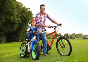 Dad and son with modern bicycles outdoors