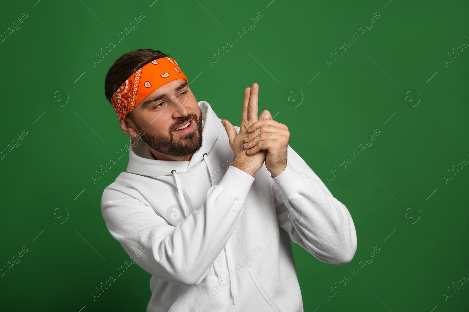 Photo of Fashionable young man in stylish outfit with bandana on green background