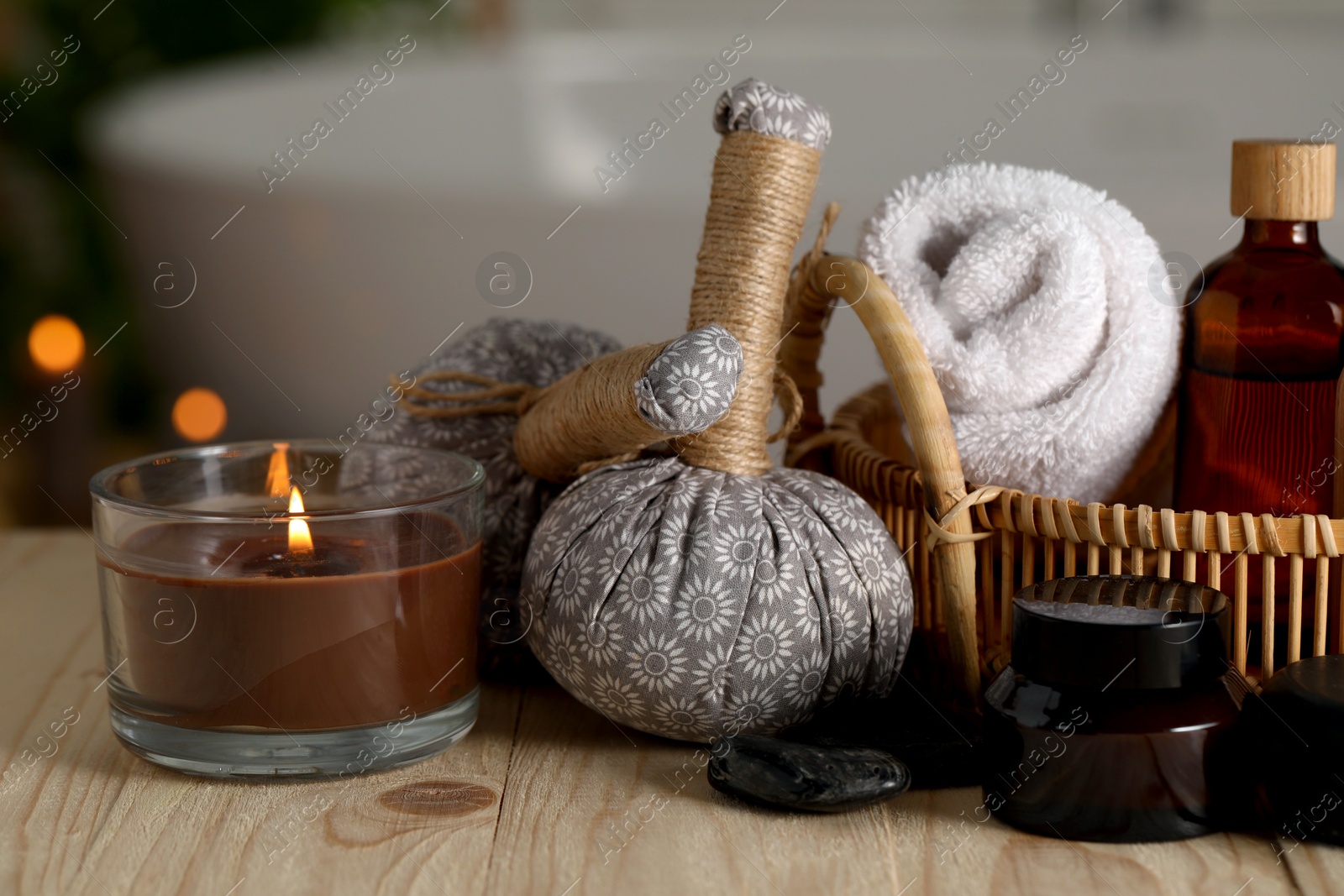 Photo of Composition with spa products and burning candle on wooden table in bathroom, closeup