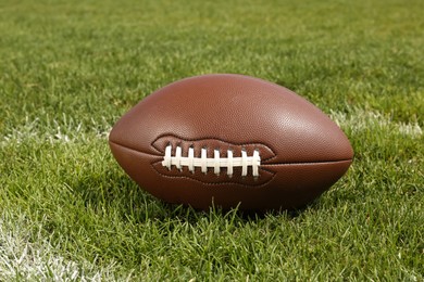 Photo of American football ball on green field grass outdoors