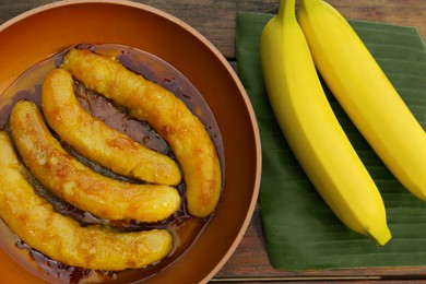 Photo of Delicious fresh and fried bananas on wooden table, flat lay