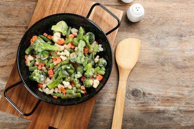 Tasty frozen vegetable mix on wooden table, flat lay