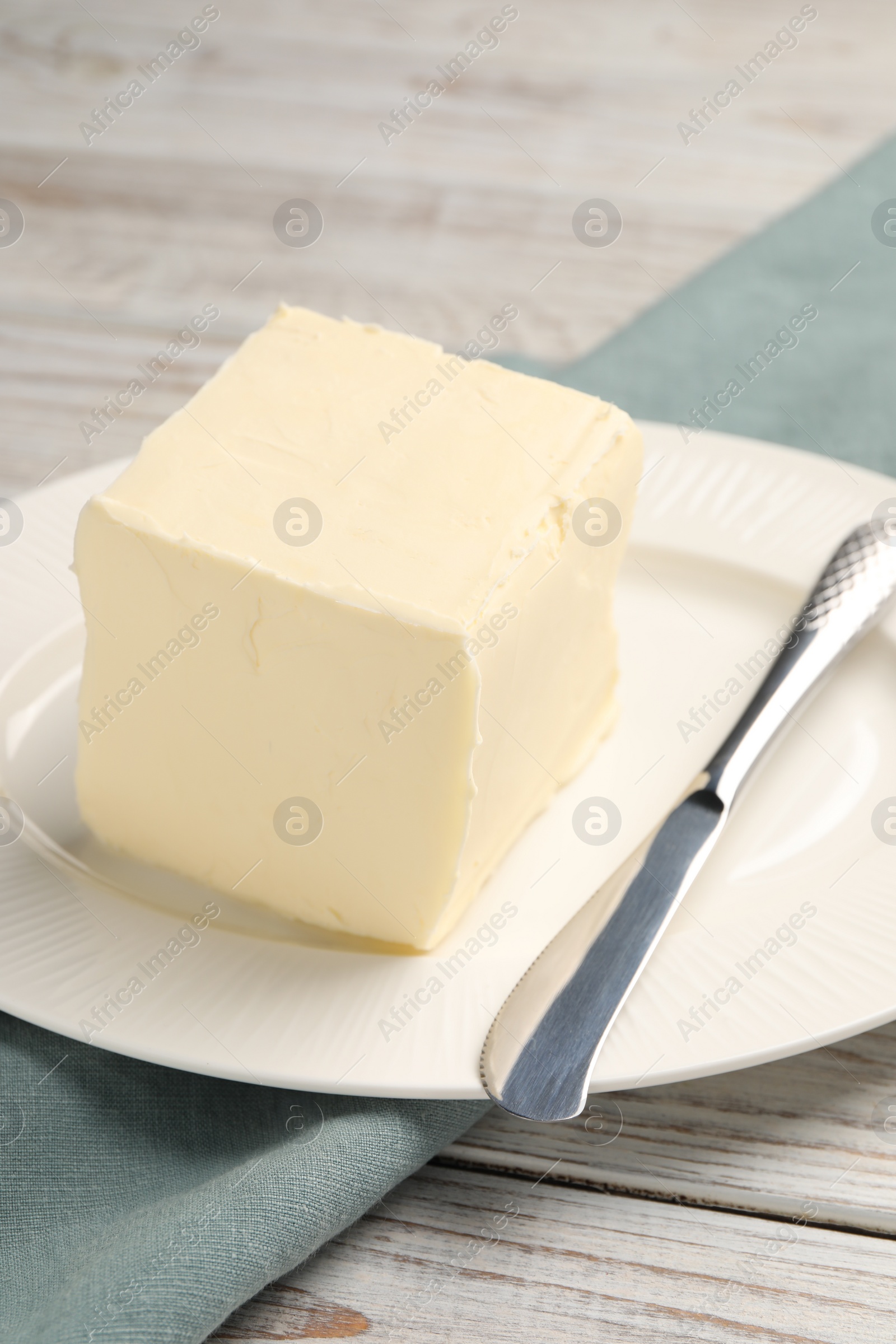 Photo of Block of tasty butter and knife on white wooden table