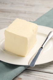 Photo of Block of tasty butter and knife on white wooden table