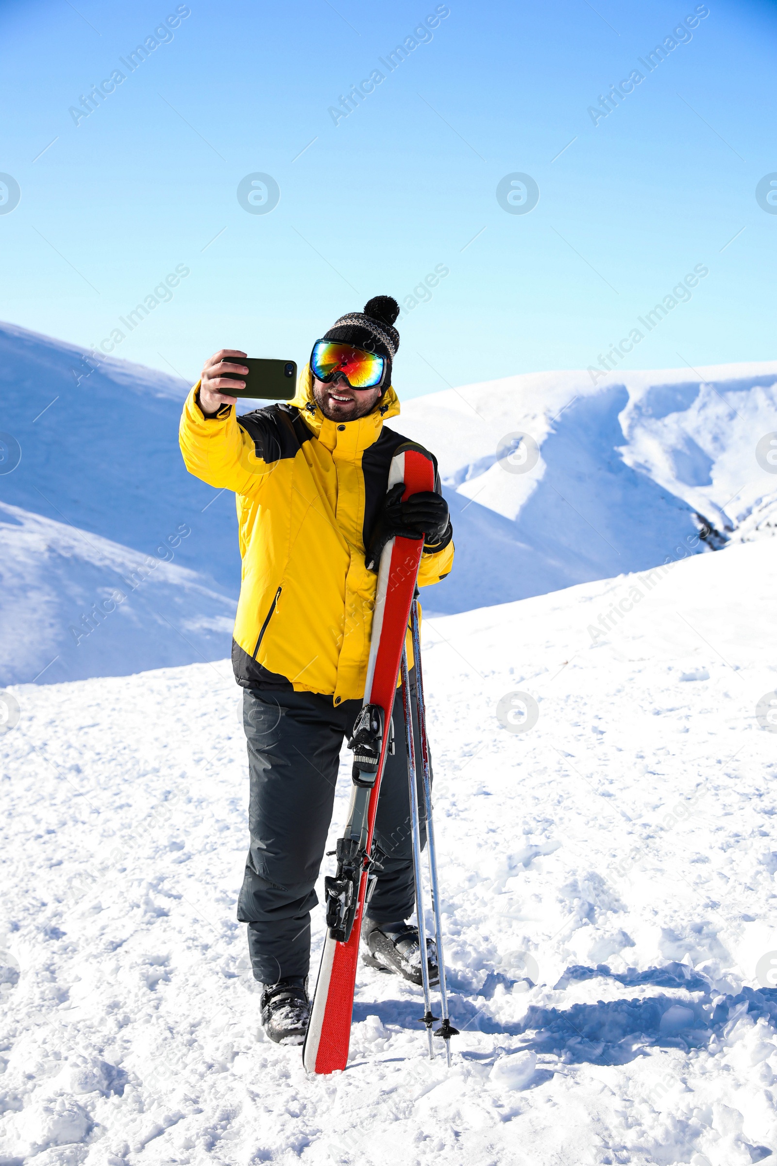 Photo of Young man with ski taking selfie on hill. Winter vacation