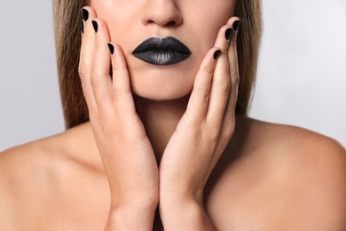 Beautiful woman with stylish nail polish on grey background, closeup