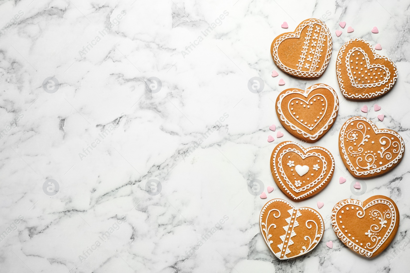 Photo of Tasty heart shaped gingerbread cookies on white marble table, flat lay. Space for text