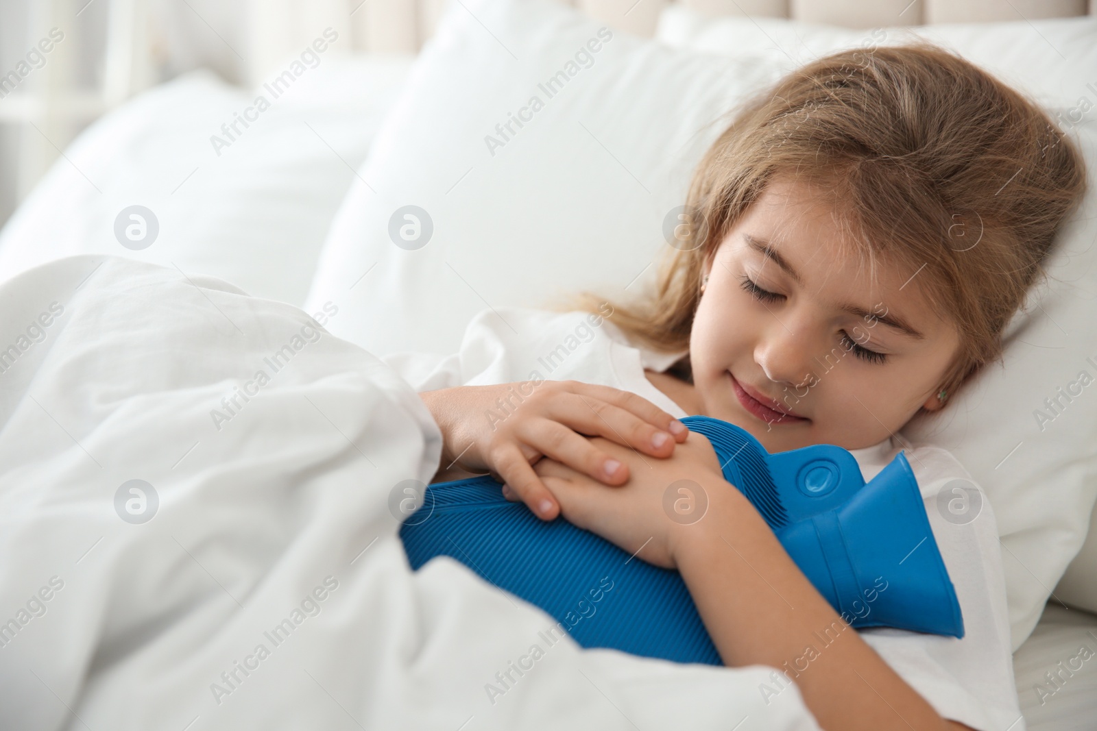 Photo of Ill girl with hot water bottle suffering from cold in bed at home