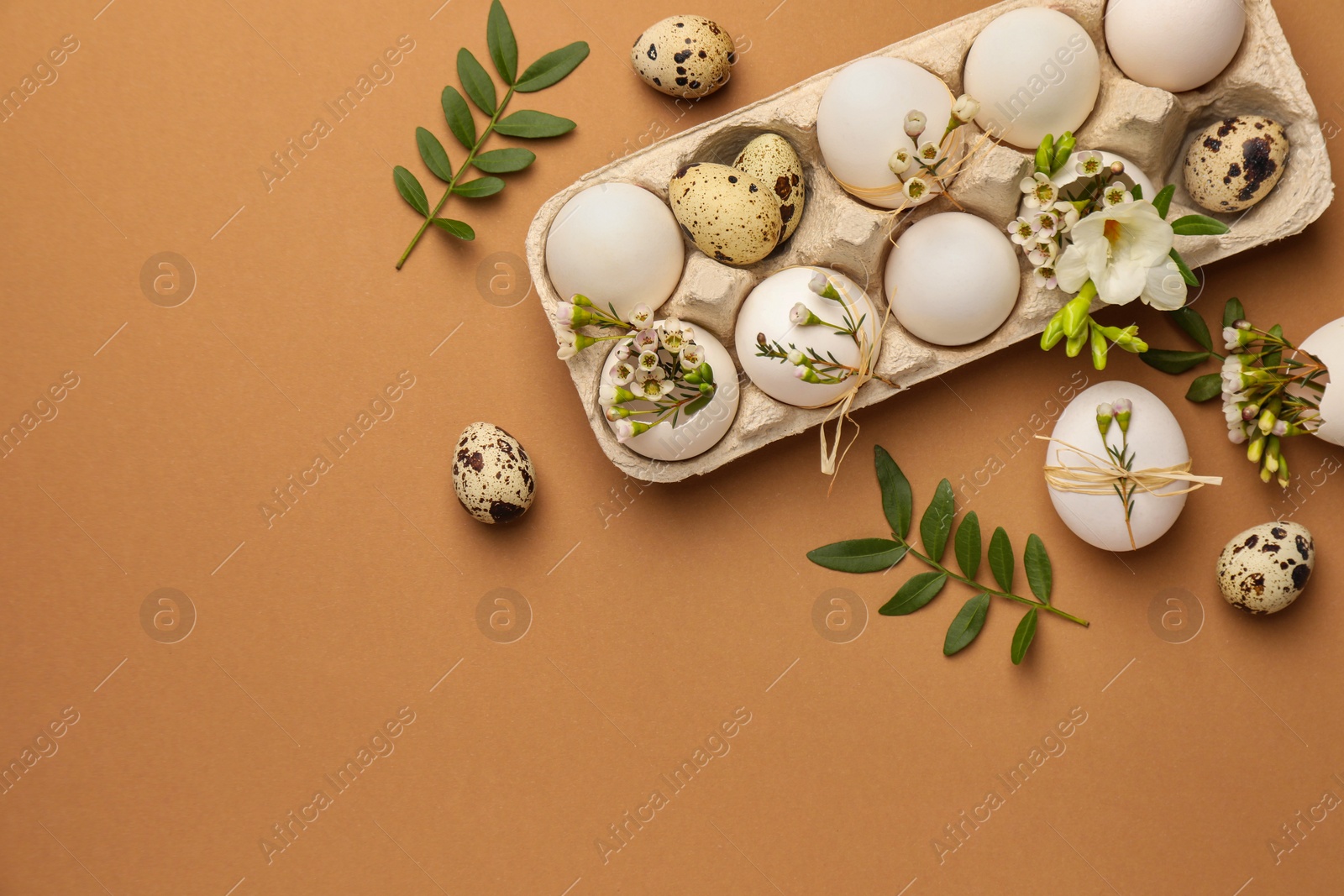 Photo of Happy Easter. Festive composition with eggs and floral decor on brown background, flat lay. Space for text