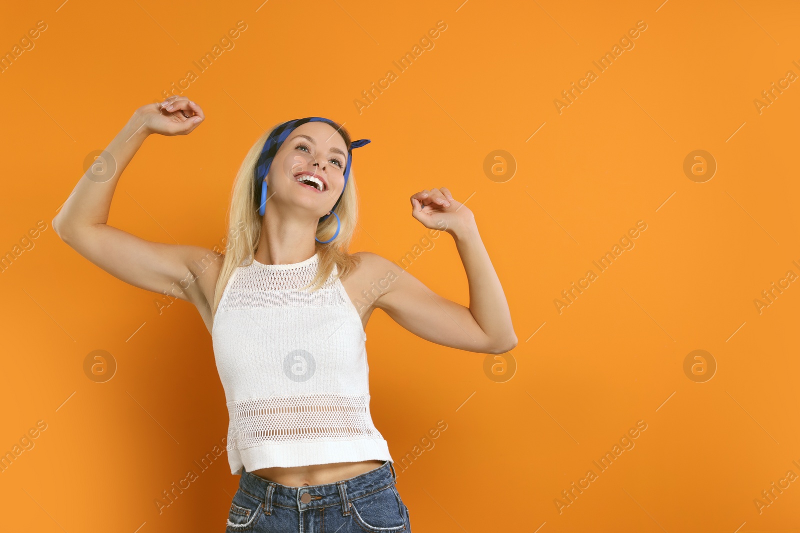 Photo of Portrait of smiling hippie woman on orange background. Space for text