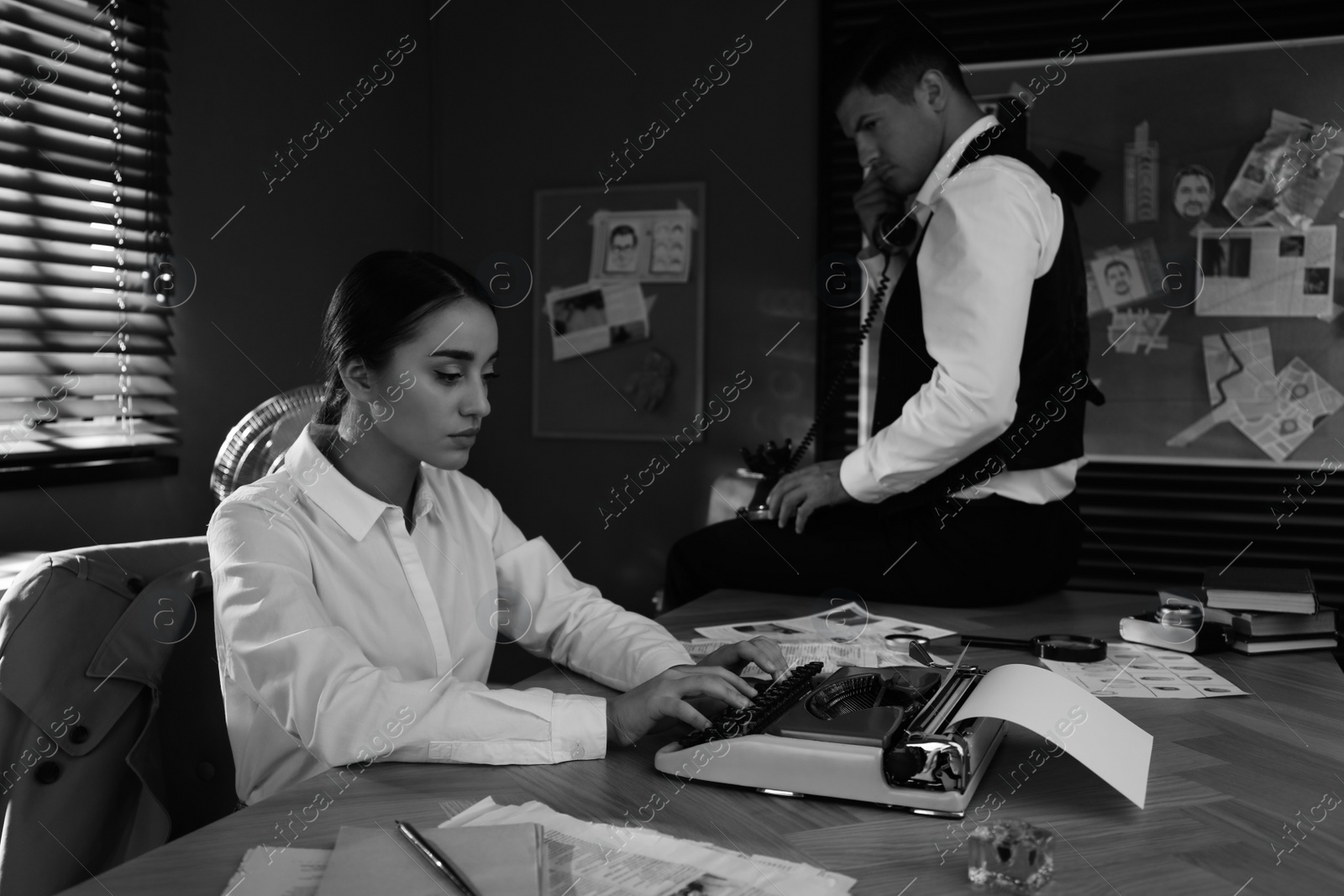 Photo of Old fashioned detective and her colleague working in office. Black and white effect