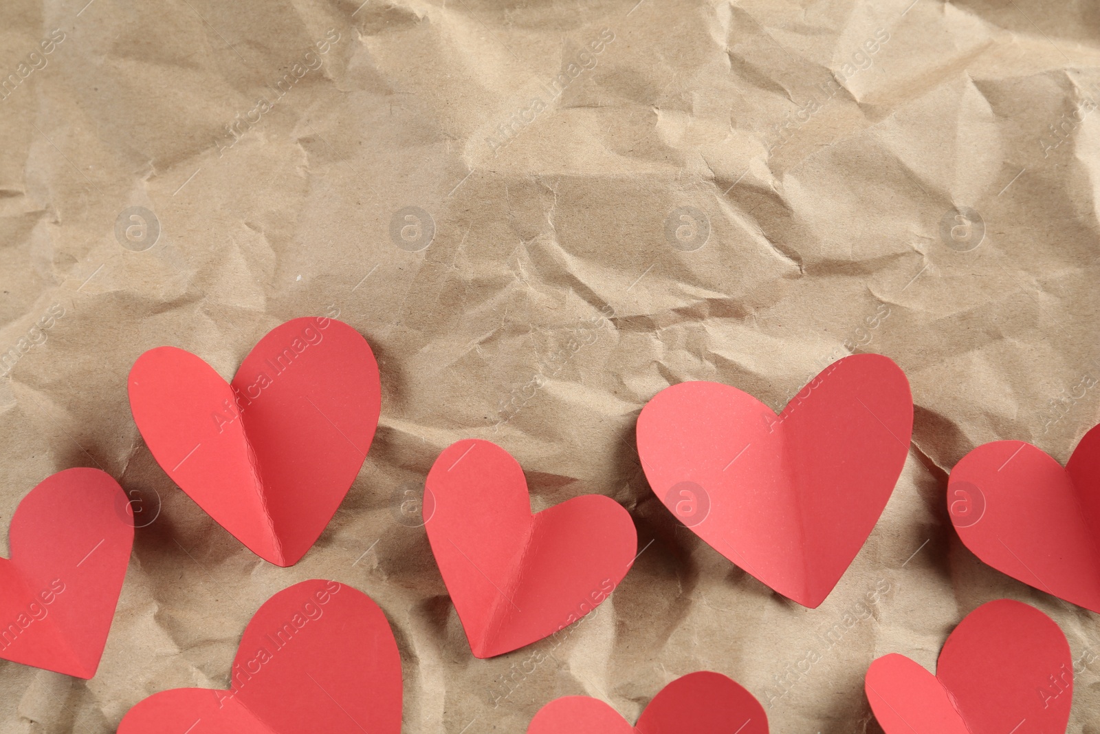 Photo of Red hearts on crumpled kraft paper, flat lay with space for text. St. Valentine's day