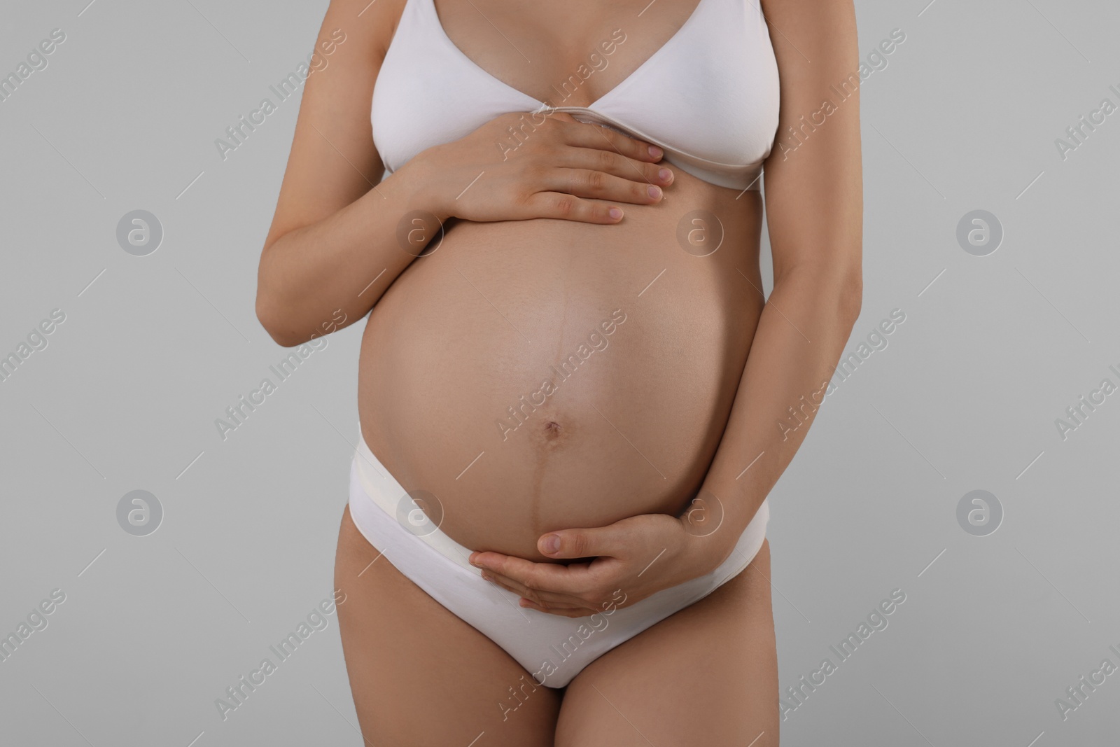 Photo of Pregnant woman in stylish comfortable underwear on grey background, closeup