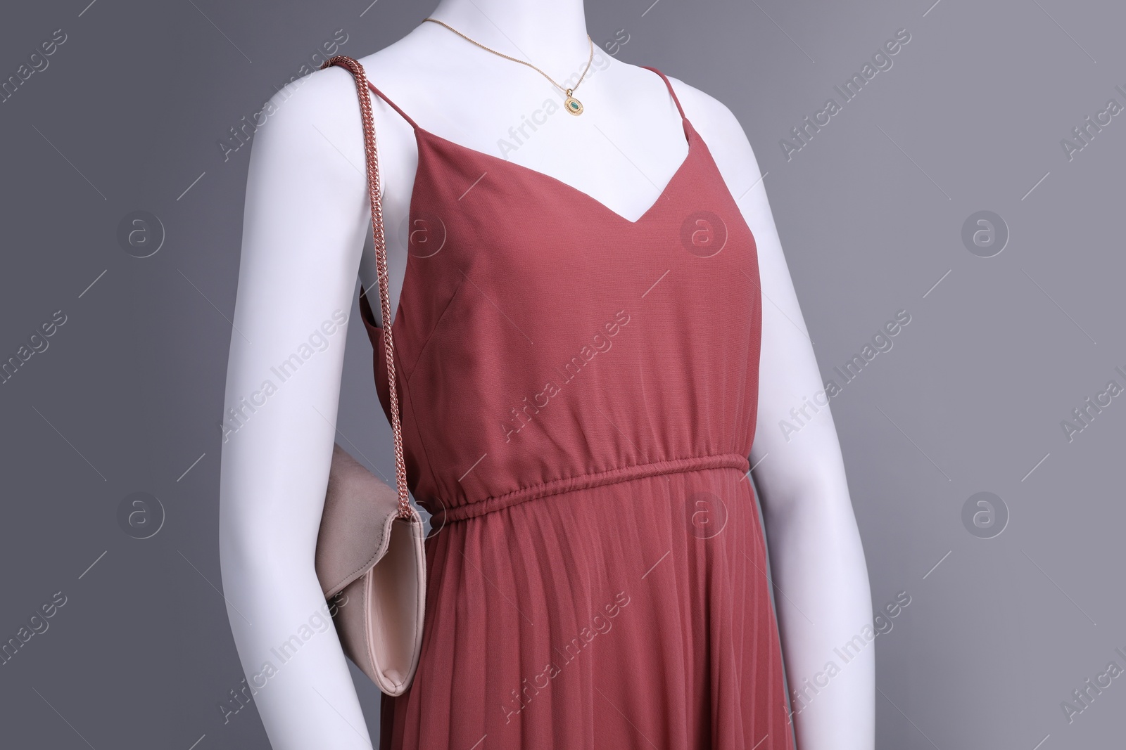 Photo of Female mannequin with necklace and bag dressed in stylish red dress on grey background