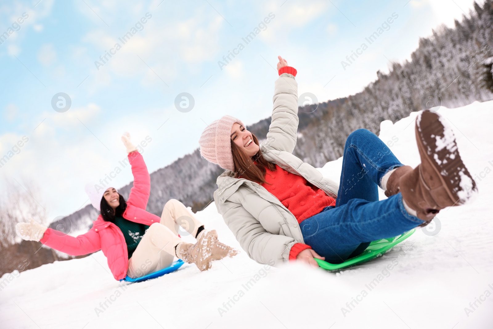 Photo of Happy friends having fun and sledding on snowy day. Winter vacation