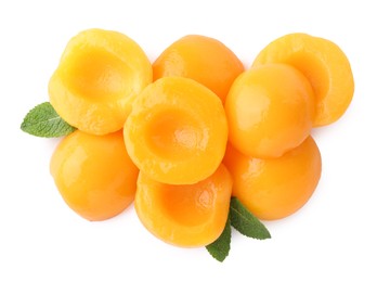 Halves of canned peaches with mint leaves isolated on white, top view