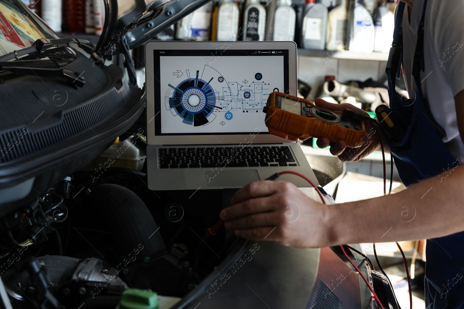 Photo of Mechanic with laptop doing car diagnostic at automobile repair shop, closeup