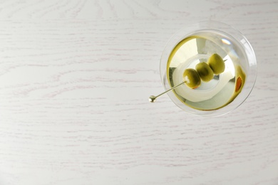 Glass of Classic Dry Martini with olives on wooden table, top view. Space for text