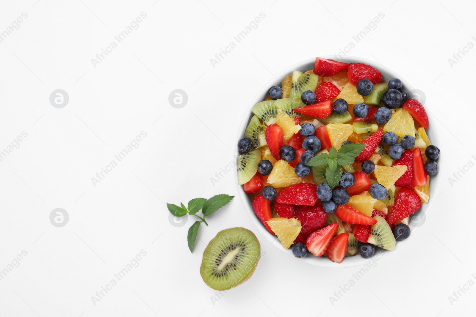 Photo of Yummy fruit salad in bowl on white background, top view. Space for text