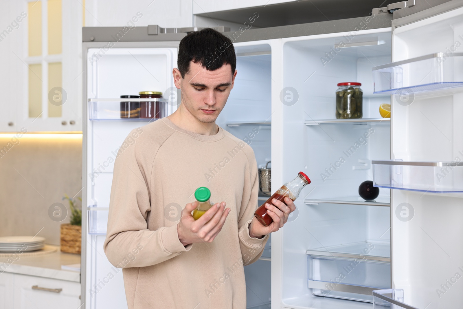 Photo of Man with sauces near empty refrigerator in kitchen