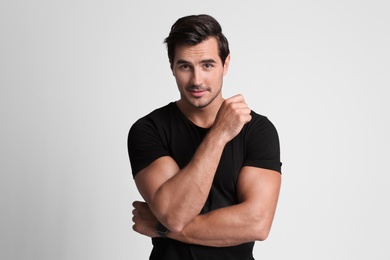 Portrait of handsome young man in black t-shirt on grey background