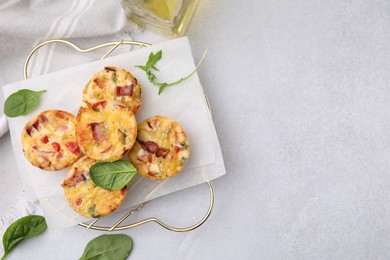 Photo of Freshly baked bacon and egg muffins with cheese on light gray table, flat lay. Space for text