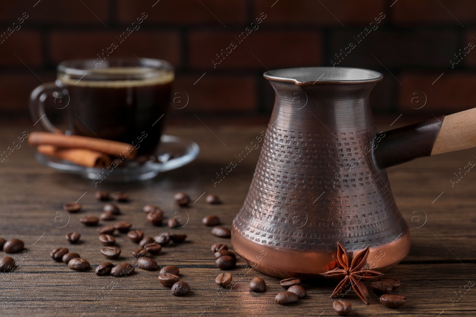 Photo of Turkish coffee in cezve and cup, beans and spices on wooden table. Space for text