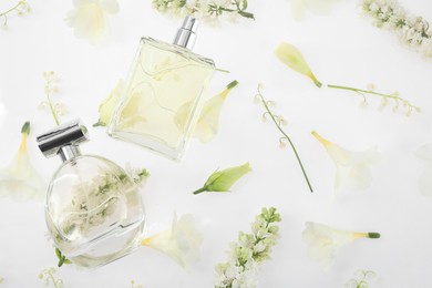 Luxury perfumes on spring floral decor, top view