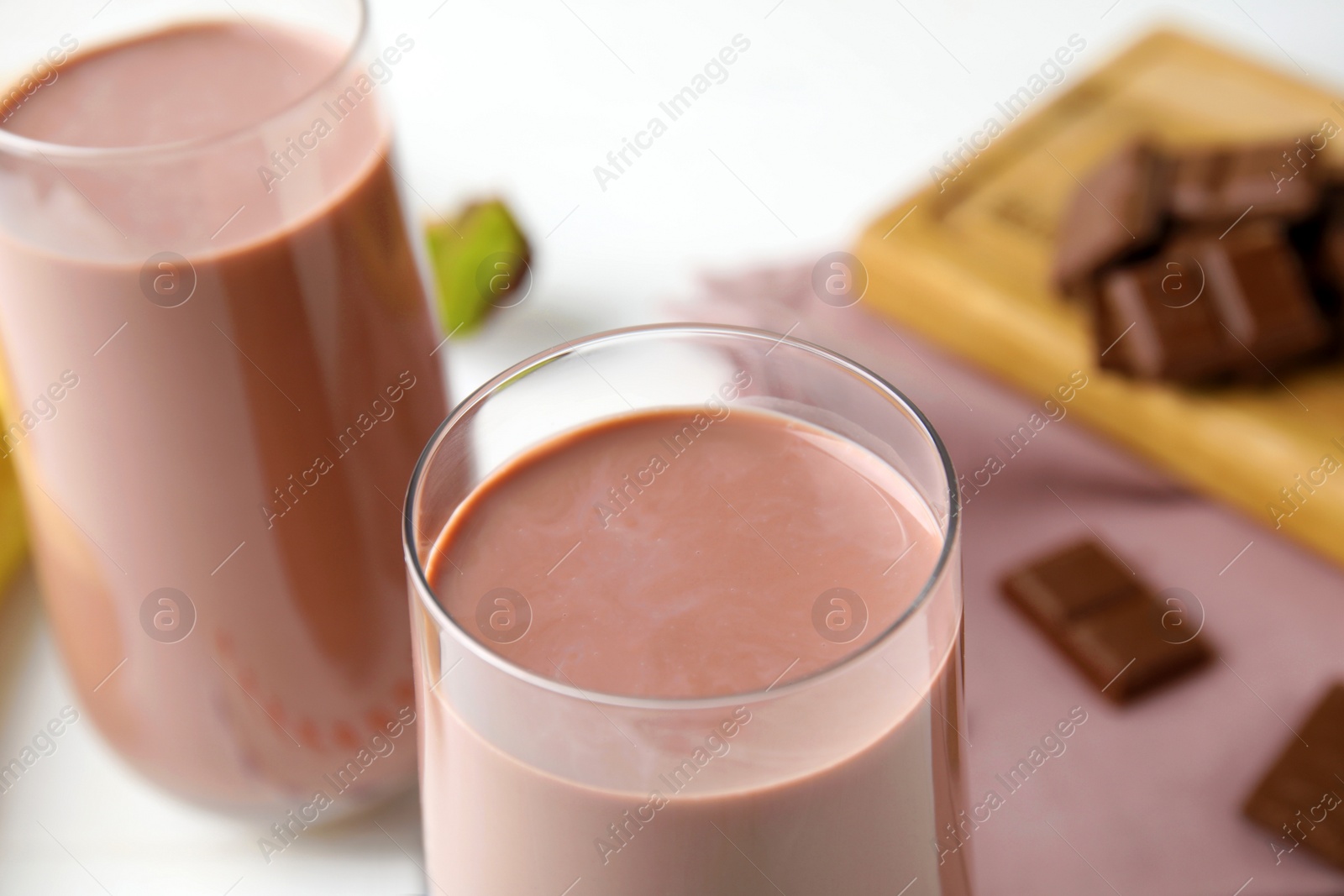 Photo of Fresh yummy chocolate milk on white table, closeup