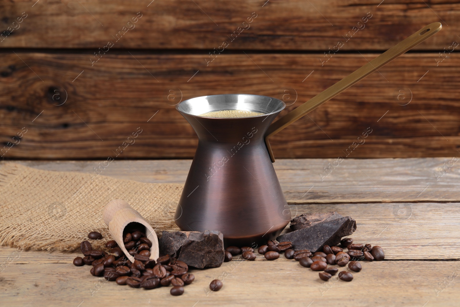 Photo of Hot turkish coffee pot, beans and chocolate on wooden table