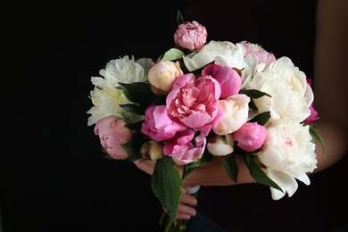 Photo of Woman with bouquet of beautiful peonies on black background, closeup