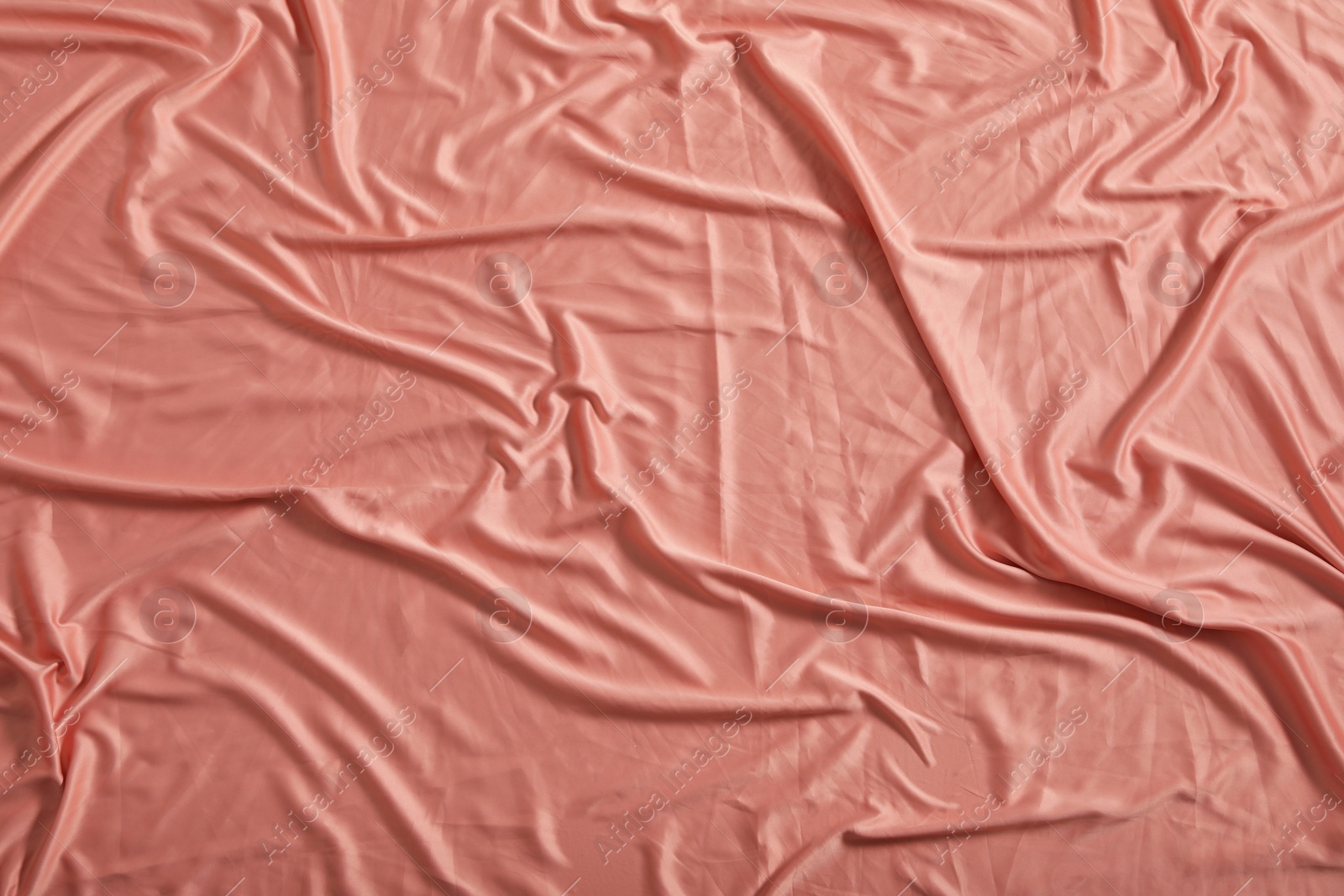 Photo of Crumpled coral fabric as background, closeup view