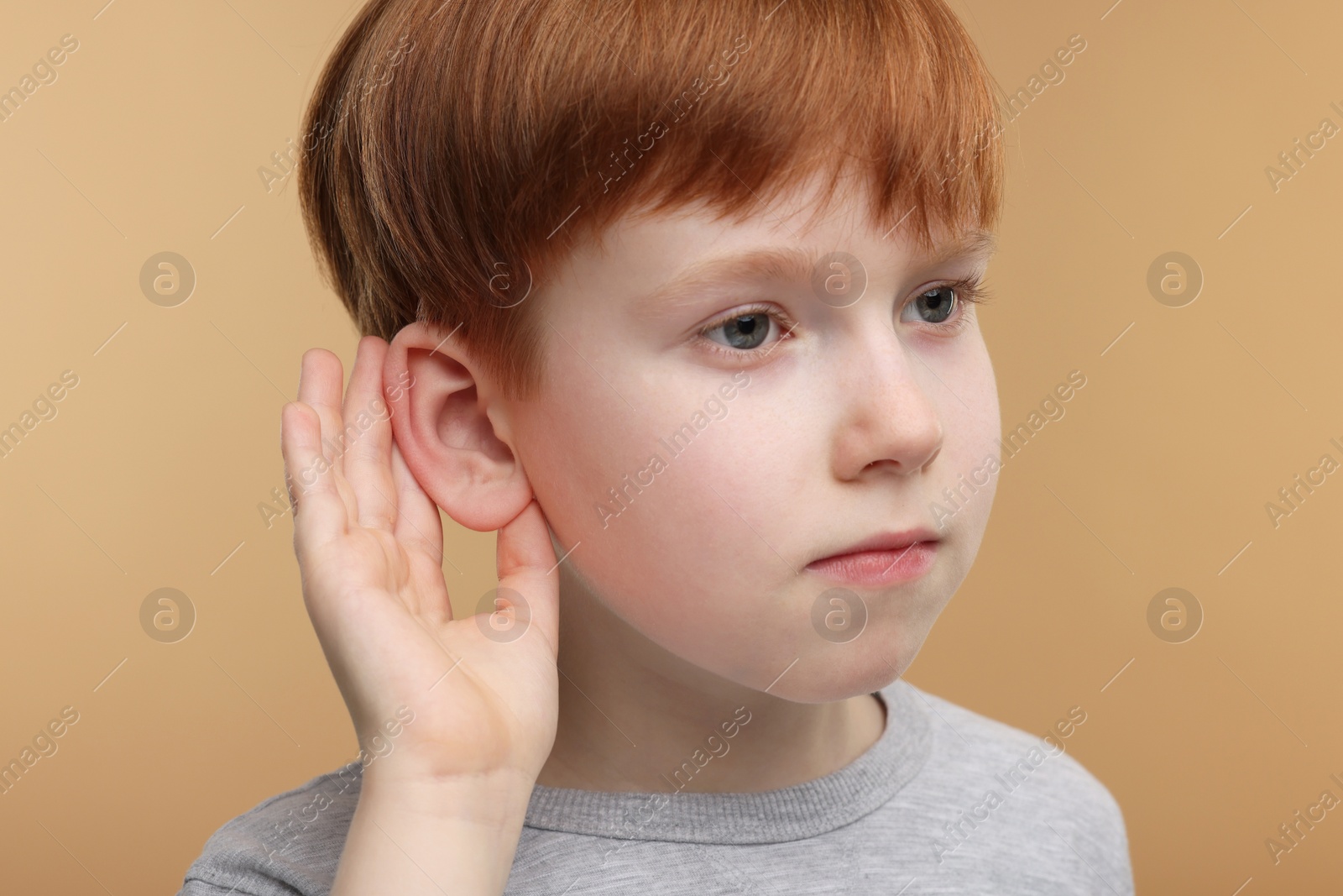 Photo of Little boy with hearing problem on pale brown background, closeup