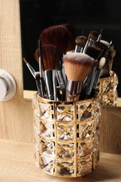 Set of professional makeup brushes near mirror on wooden table